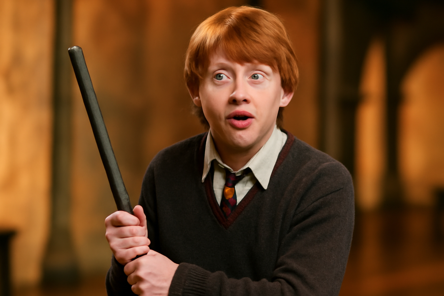 Ron Weasley with a humorous expression, holding a broomstick awkwardly in his Gryffindor uniform. The warm, inviting background reflects his playful and loyal character traits.