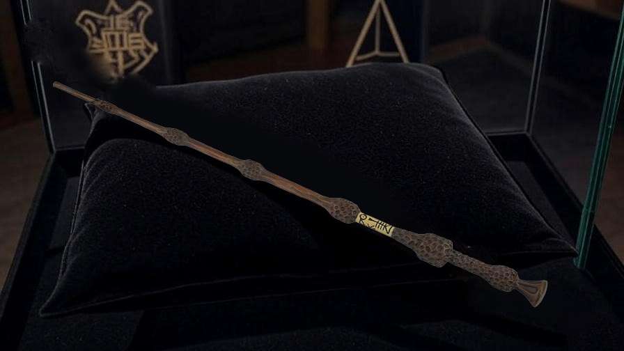 Elder Wand replica displayed on a velvet cushion in a glass case, showcasing its intricate design for Harry Potter collectors. 