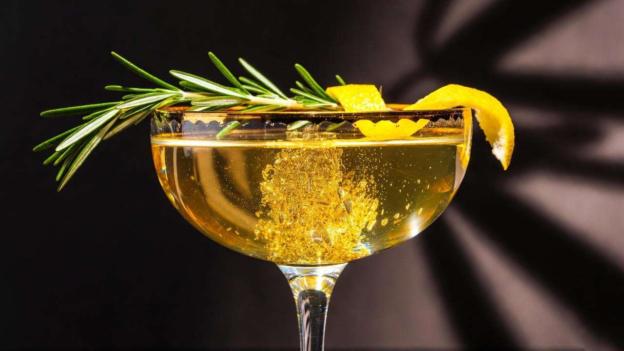 Elegant golden boozy liquid luck drink with edible gold shimmer and rosemary garnish – Felix Felicis cocktail recipe.