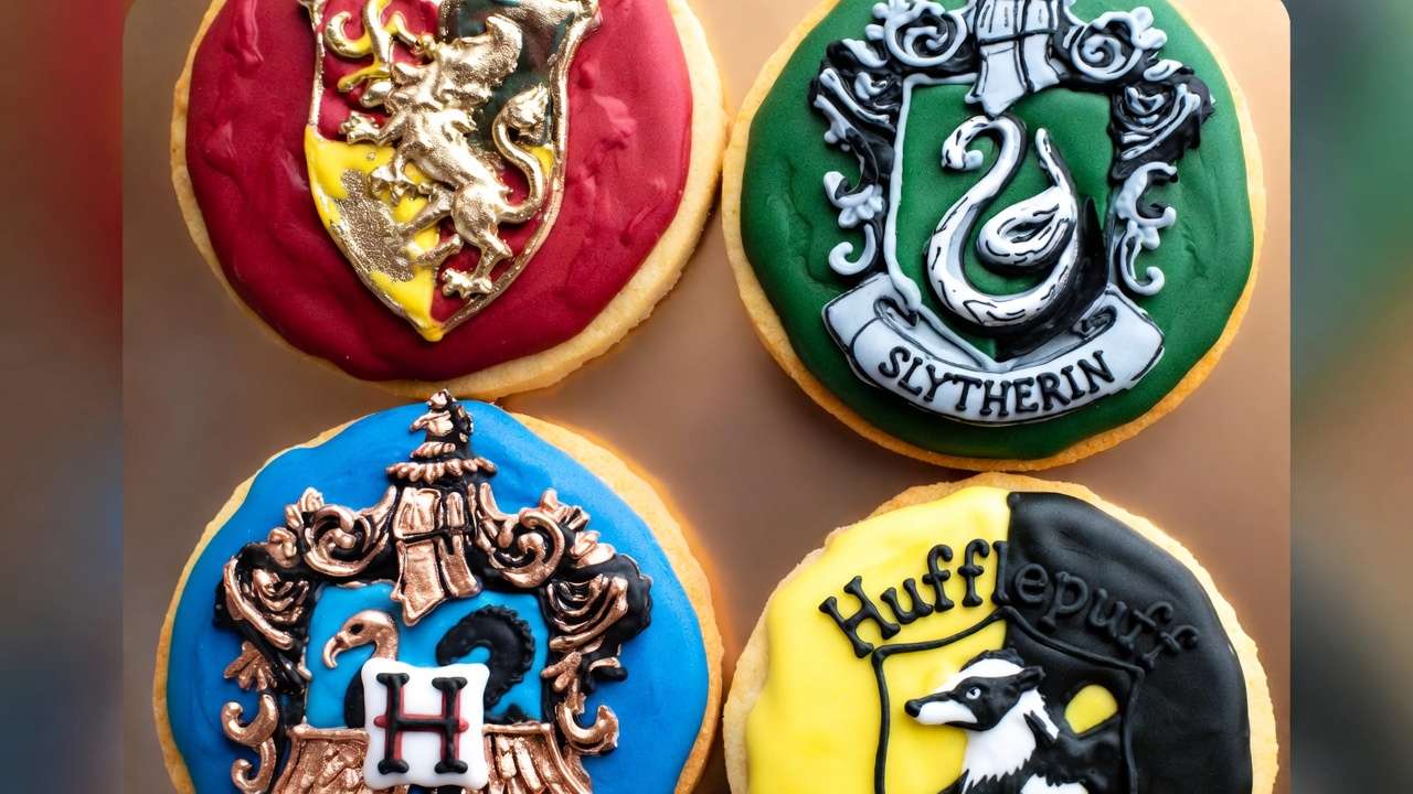 Four Hogwarts house crest cookies with detailed royal icing for Harry Potter parties