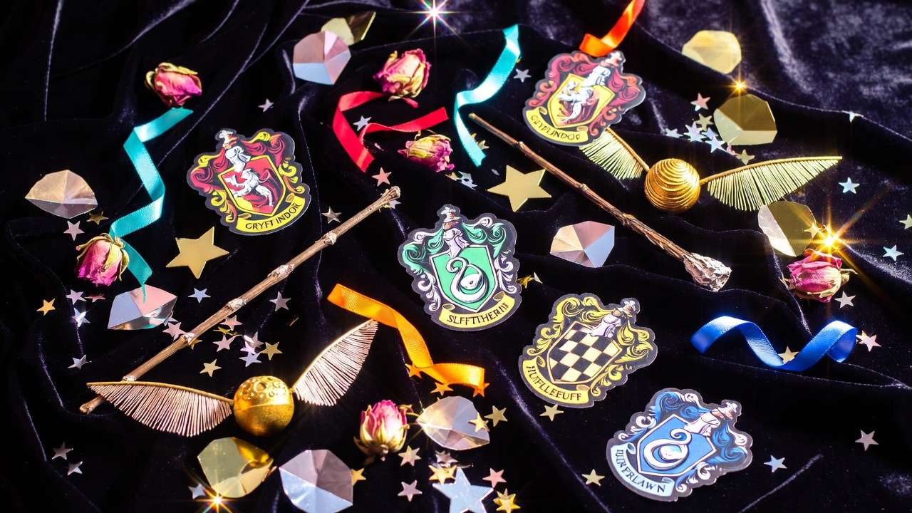 Flat lay of personalized Harry Potter house crests, wands and ribbons for custom birthday invitations