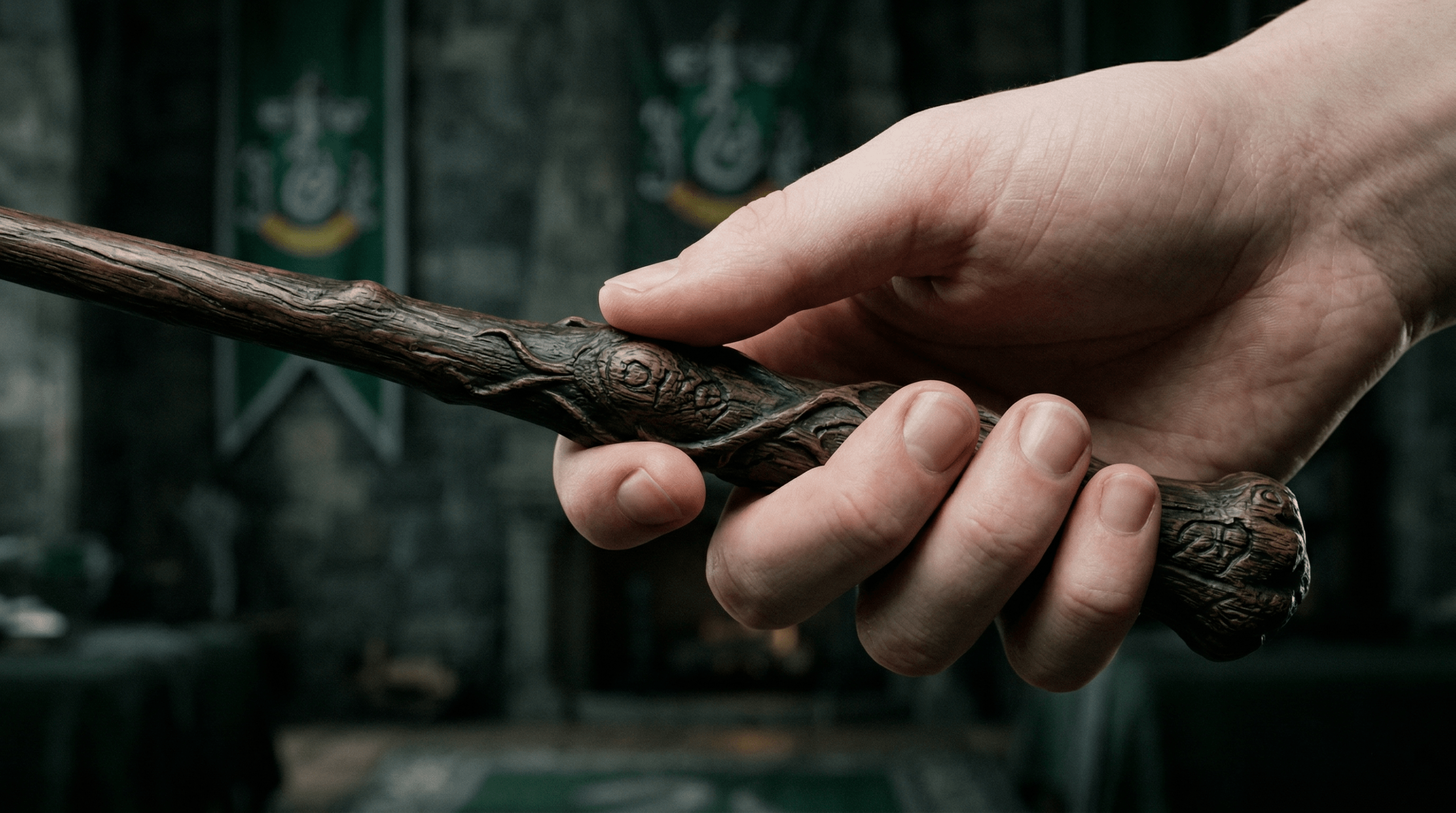 A close-up of Draco Malfoy’s 10-inch Hawthorne wood wand with silver Slytherin banners in the background.
