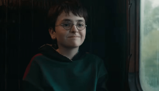 Harry Potter smiling at something with a reassuring grin