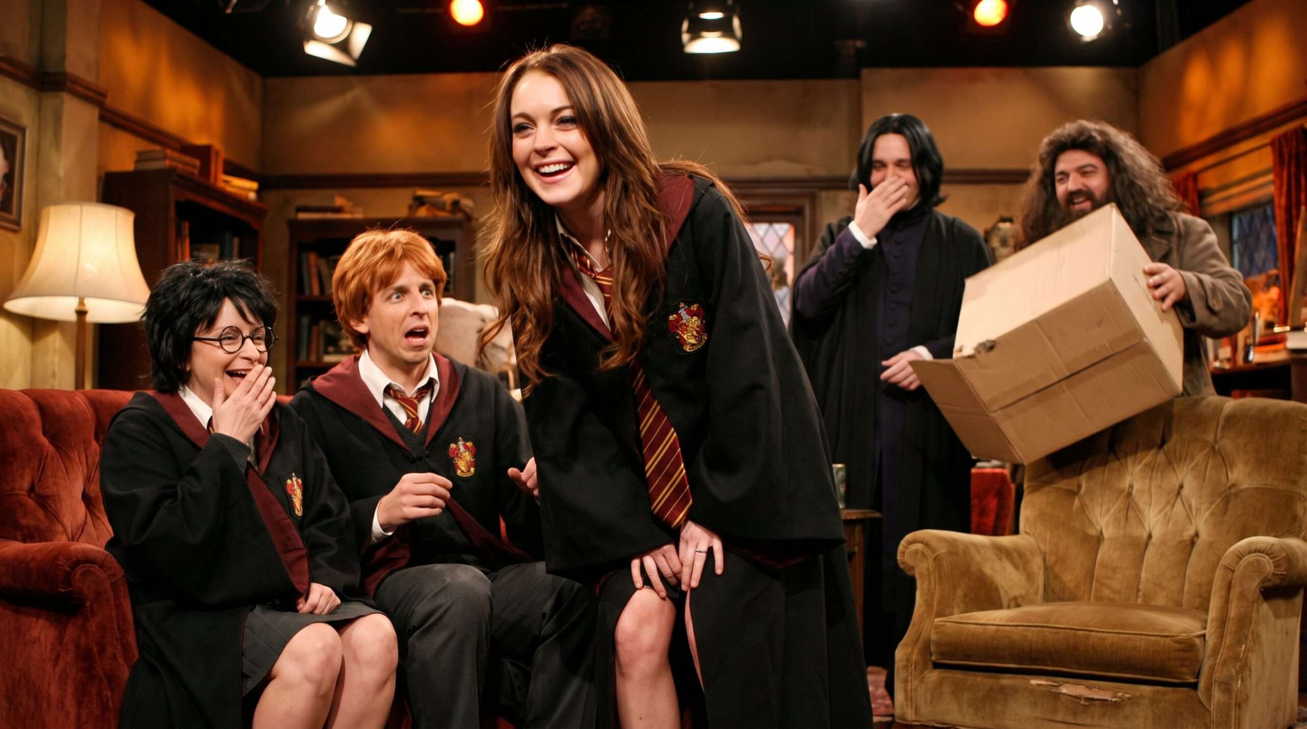 A wide-angle SNL sketch photograph of Lindsay Lohan (Hermione) on stage with Rachel Dratch (Harry Potter), Seth Meyers (Ron), and the SNL cast as Snape and Hagrid, all visibly laughing and breaking character.